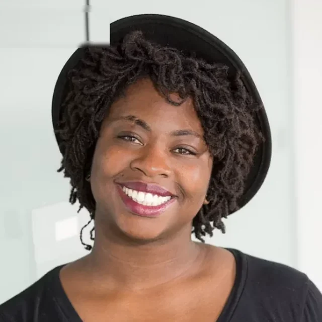 Au pair smiling warmly in a black top against a pale background