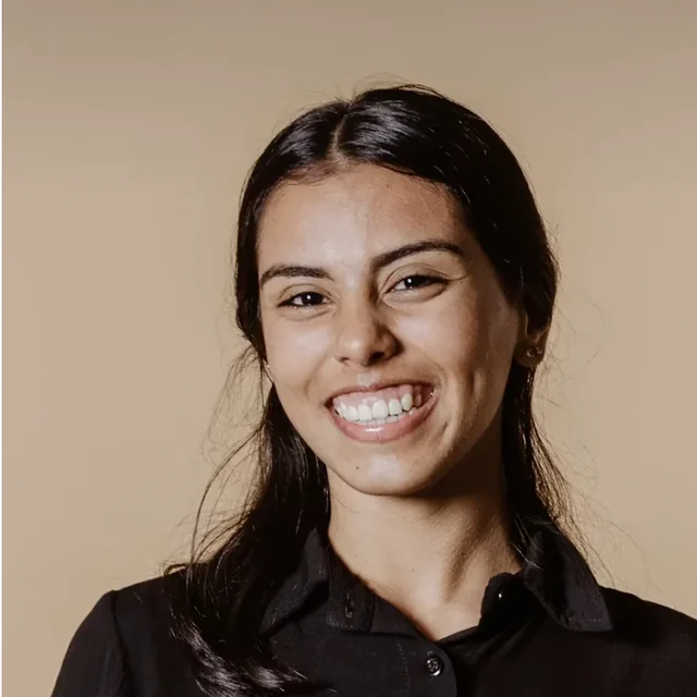 Au pair in a dark collared shirt smiling against a warm plain background