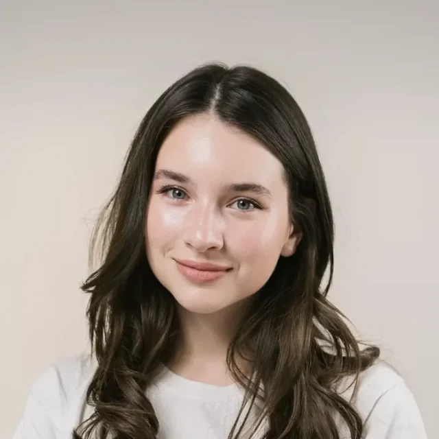 Au pair in a plain white t-shirt smiling softly against a light background